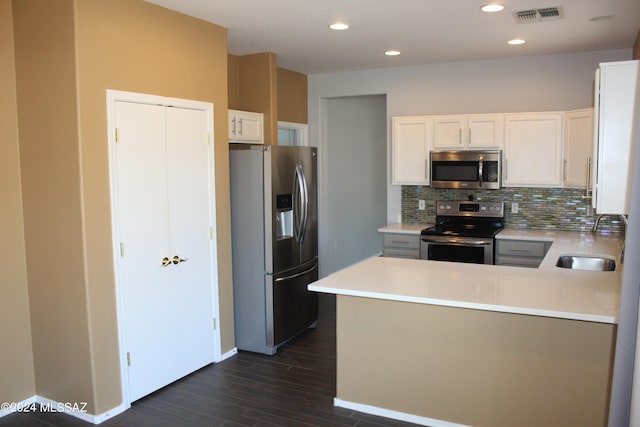 kitchen with dark wood-style flooring, a peninsula, light countertops, tasteful backsplash, and stainless steel appliances