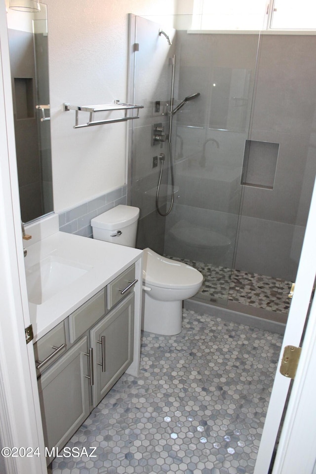 bathroom with a shower with door, tile patterned floors, vanity, and toilet