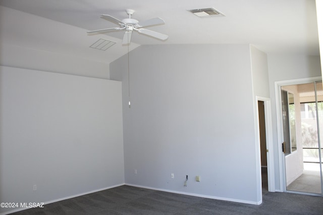 empty room featuring a ceiling fan, visible vents, vaulted ceiling, baseboards, and dark colored carpet