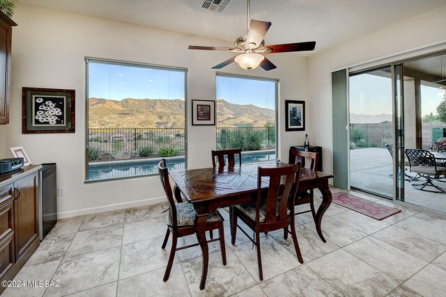 tiled dining area with a mountain view, a wealth of natural light, and ceiling fan