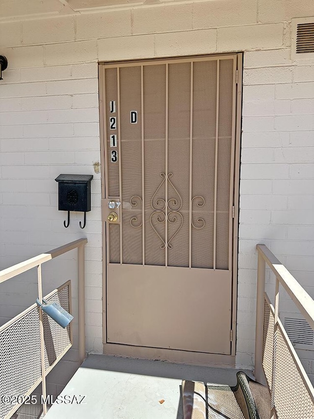 entrance to property featuring visible vents and concrete block siding