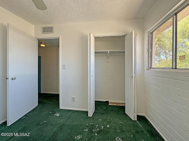 unfurnished bedroom with visible vents, carpet flooring, a textured ceiling, and a closet