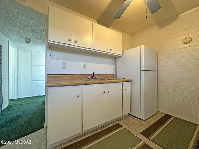 kitchen with white cabinets, a ceiling fan, a sink, and freestanding refrigerator