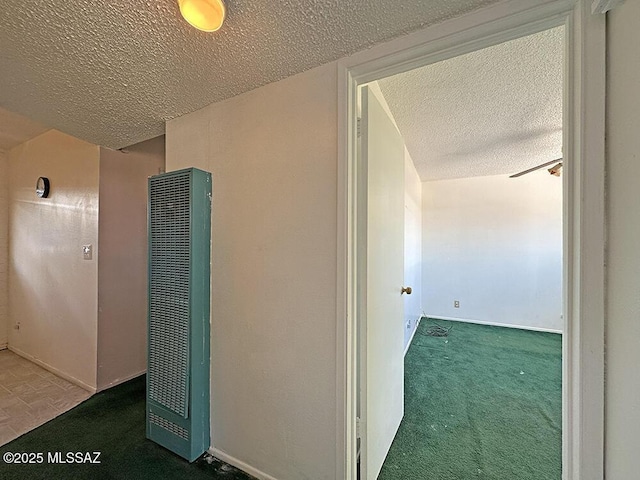 hall featuring carpet floors, a textured ceiling, baseboards, and a heating unit