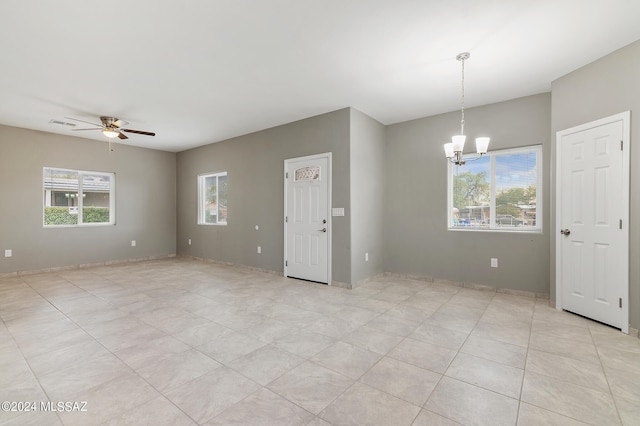 tiled spare room with ceiling fan with notable chandelier