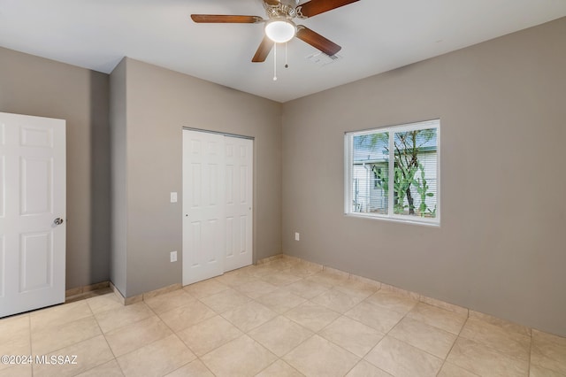 unfurnished bedroom with light tile patterned flooring, a closet, and ceiling fan