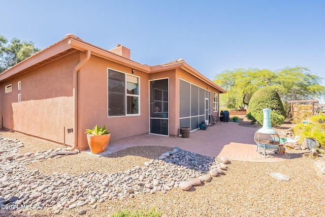 rear view of property with a sunroom and a patio