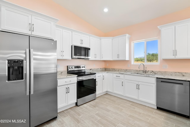 kitchen with sink, vaulted ceiling, stainless steel appliances, and white cabinets