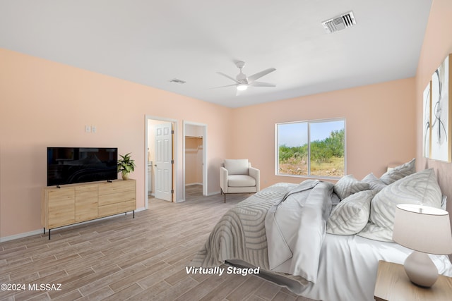 bedroom with a spacious closet, light hardwood / wood-style flooring, a closet, and ceiling fan