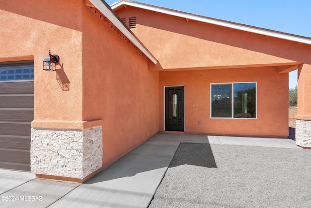 view of exterior entry featuring a garage and a patio