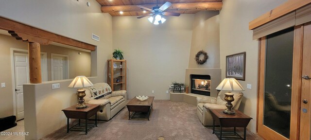 sitting room with wooden ceiling, ceiling fan, a towering ceiling, beam ceiling, and carpet floors