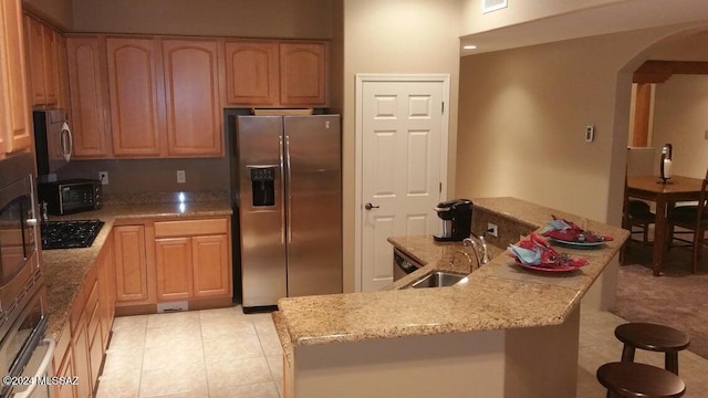 kitchen with sink, light stone countertops, and stainless steel appliances