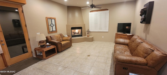 tiled living room featuring ceiling fan and a fireplace