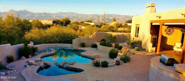 view of pool featuring a patio area, a mountain view, and a hot tub