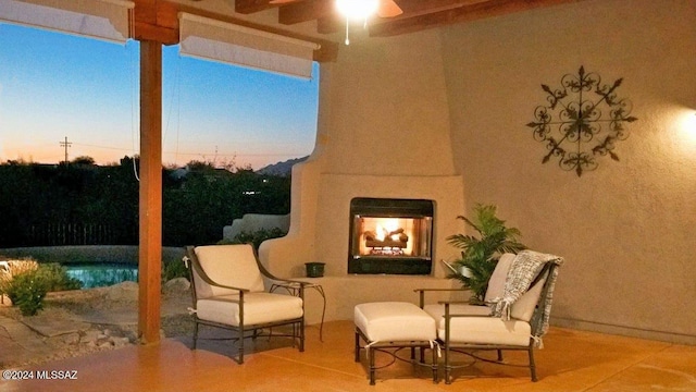 patio terrace at dusk with ceiling fan and an outdoor fireplace