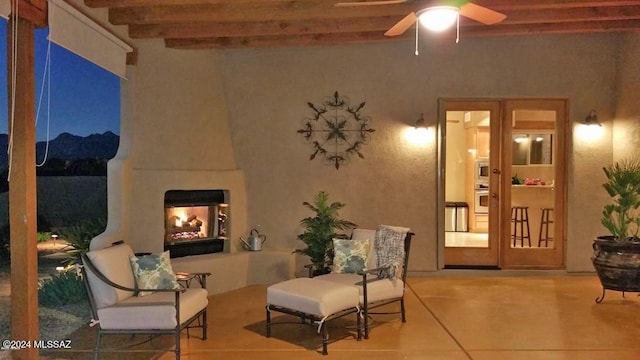 sitting room with beam ceiling, exterior fireplace, and ceiling fan