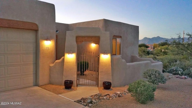 exterior entry at dusk featuring a mountain view and a garage