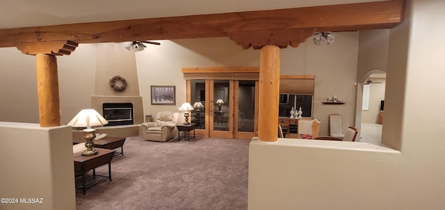 living room with carpet flooring, ceiling fan, a fireplace, and beamed ceiling