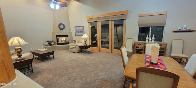 interior space featuring a high ceiling, french doors, carpet flooring, ceiling fan, and a large fireplace