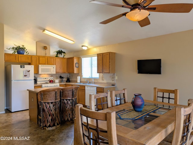 dining space with sink, ceiling fan, and vaulted ceiling