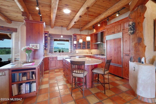 kitchen with beamed ceiling, decorative light fixtures, a center island, and rail lighting