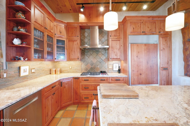 kitchen with pendant lighting, wall chimney range hood, decorative backsplash, and paneled fridge