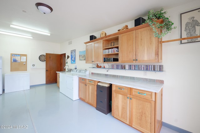 kitchen featuring light brown cabinets, stainless steel fridge, sink, and washing machine and clothes dryer