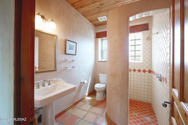 bathroom with tile patterned flooring, wood ceiling, tiled shower, and toilet