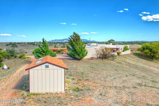 view of yard featuring a rural view, a storage shed, and a mountain view