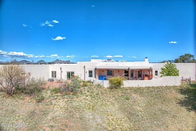 rear view of property with a mountain view and a lawn