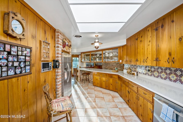 kitchen with wood walls, kitchen peninsula, backsplash, and appliances with stainless steel finishes