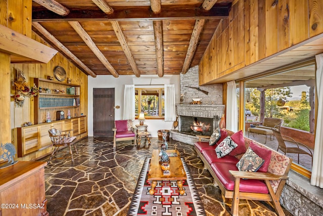 living room with a fireplace, plenty of natural light, wooden walls, and vaulted ceiling with beams