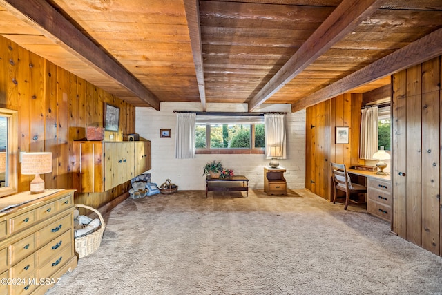 living area featuring beamed ceiling, wooden walls, and built in desk