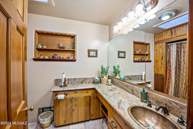 bathroom with a skylight, tile patterned floors, and vanity