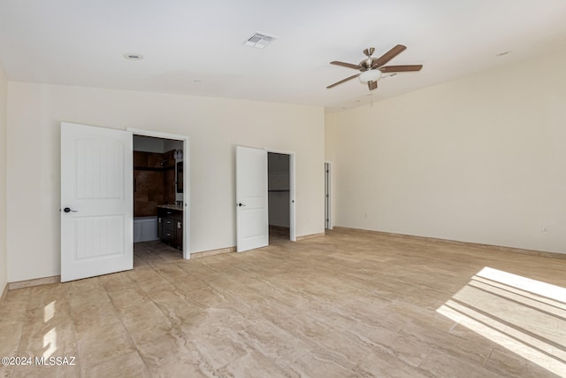 unfurnished bedroom featuring a spacious closet, connected bathroom, a closet, and ceiling fan