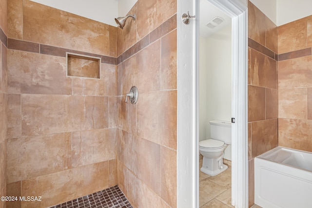 bathroom with a tile shower, toilet, and tile patterned flooring