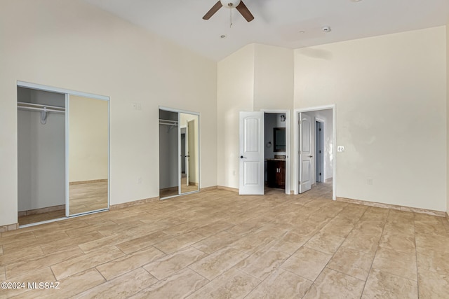 unfurnished bedroom with multiple closets, high vaulted ceiling, and ceiling fan