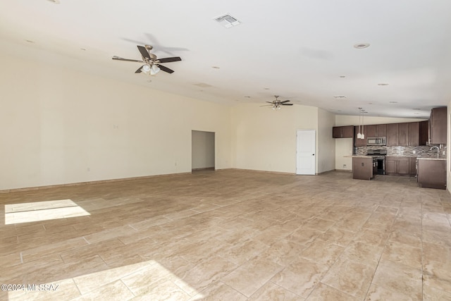 unfurnished living room with ceiling fan, vaulted ceiling, and sink