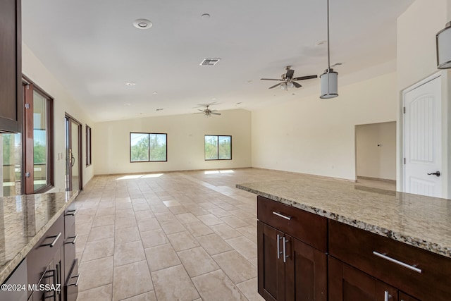 kitchen featuring light stone counters, light tile patterned flooring, lofted ceiling, and ceiling fan