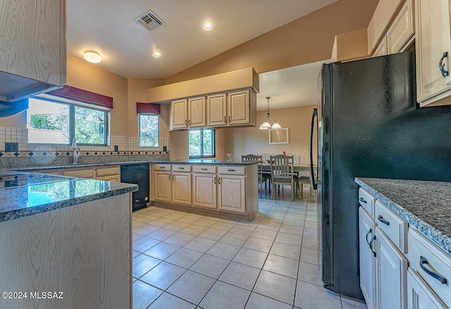 kitchen featuring kitchen peninsula, light brown cabinetry, black fridge, light tile patterned floors, and pendant lighting