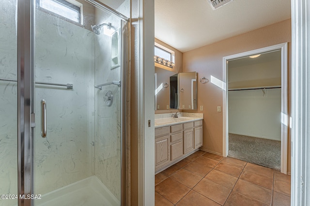 bathroom featuring tile patterned flooring, vanity, and walk in shower