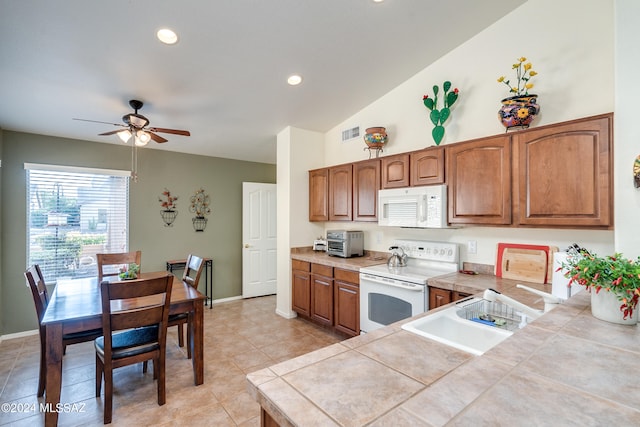 kitchen with ceiling fan, light tile patterned floors, white appliances, tile counters, and vaulted ceiling