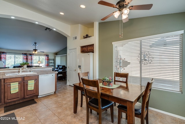 dining space with ceiling fan, light tile patterned floors, sink, and vaulted ceiling