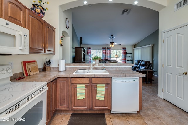 kitchen featuring white appliances, vaulted ceiling, sink, kitchen peninsula, and light tile patterned floors