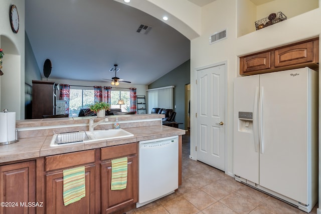 kitchen with lofted ceiling, white appliances, sink, and tile countertops