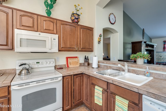 kitchen with high vaulted ceiling, white appliances, sink, and tile countertops