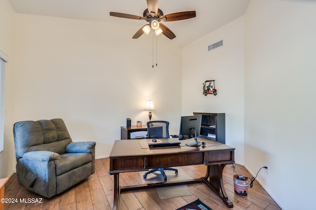 home office with ceiling fan, vaulted ceiling, and light hardwood / wood-style floors