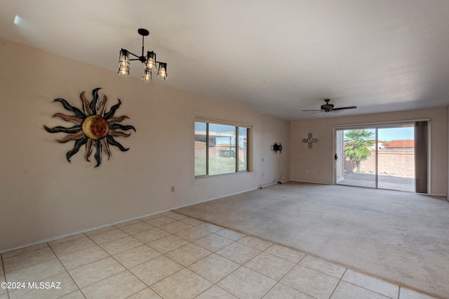 spare room featuring light colored carpet and ceiling fan with notable chandelier