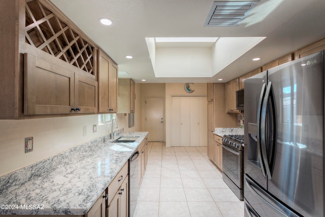 kitchen featuring light stone countertops, sink, light tile patterned floors, and stainless steel appliances