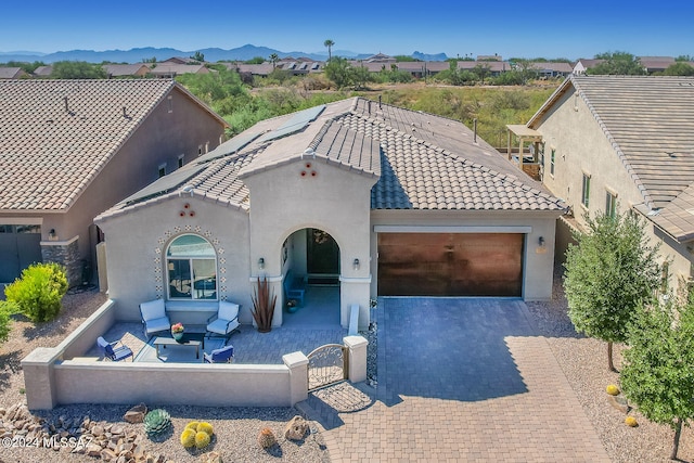 mediterranean / spanish-style house with a mountain view, a garage, an outdoor hangout area, and a patio area